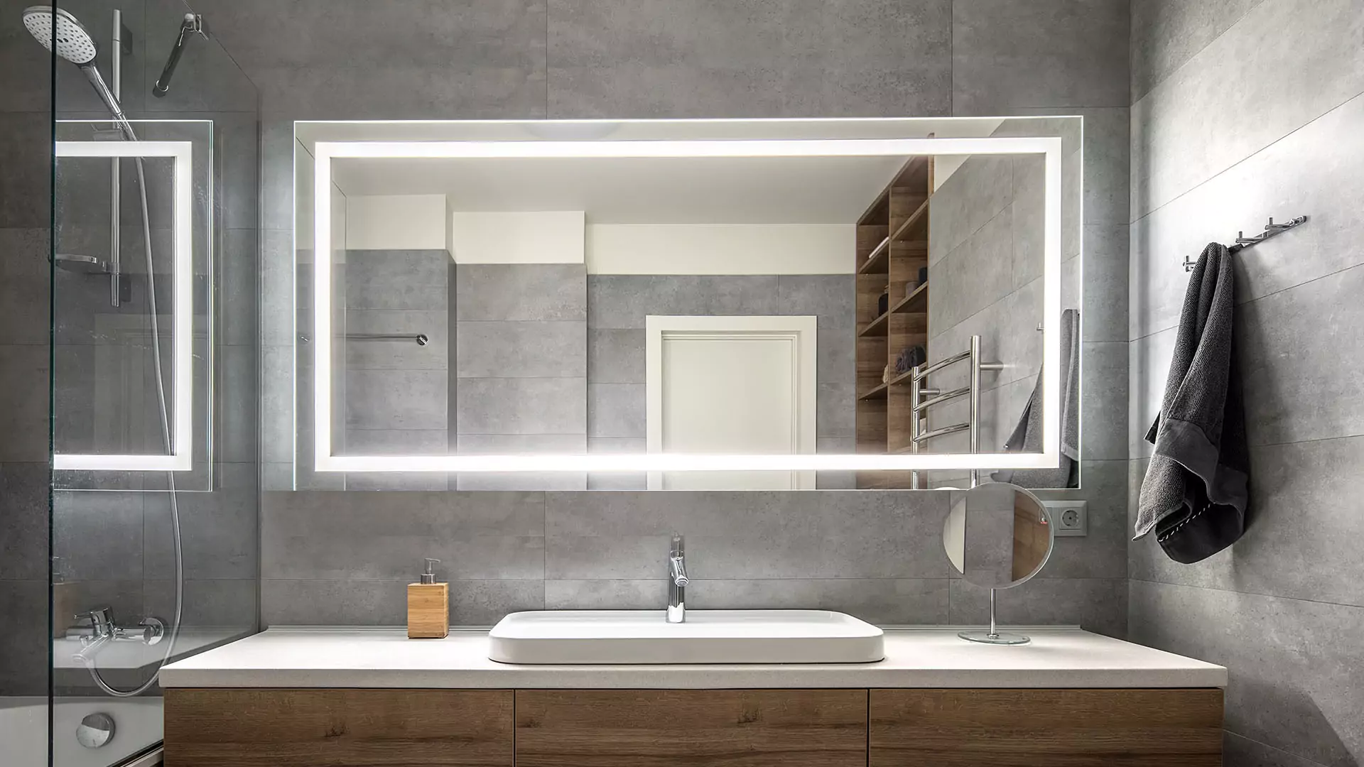 Lighted mirror above the single sink with a standing circle glass on the side.