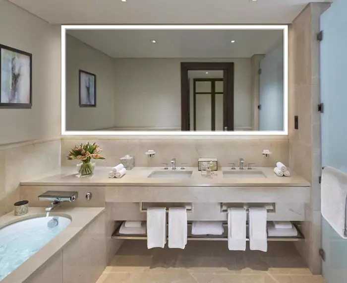 Bathroom light-framed mirror set into a cream-colored wall in a restroom.