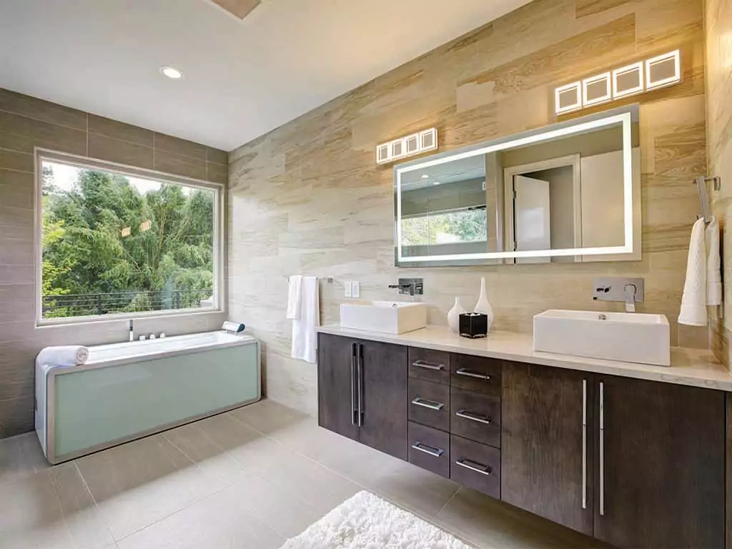 Wooden dark brown countertop bathroom cabinet with a custom-lighted mirror in a class restroom.