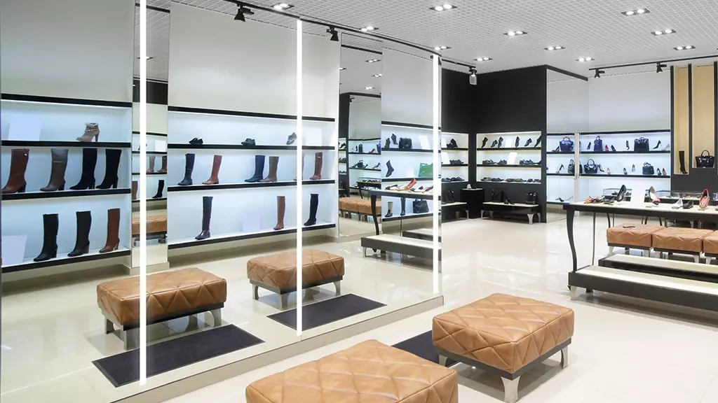 Store with an elegantly lit mirror for customers to try out products with shoe bench seating.