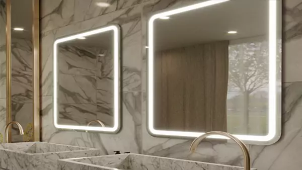 Custom lighted mirror provides a touch of fancy and luxury to a double bathroom sink in a hotel.