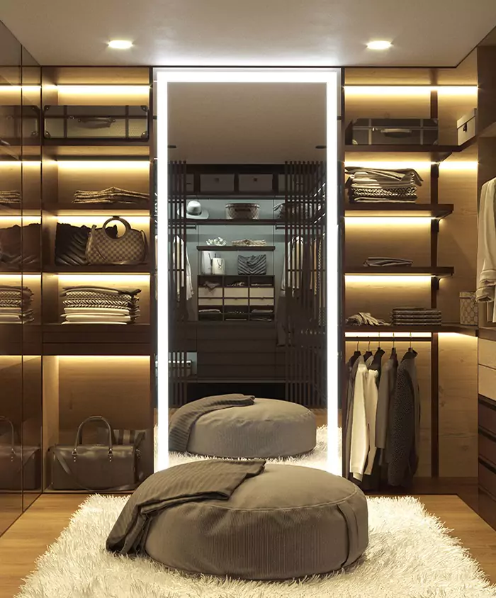 A functional walk-in closet with a contemporary lighted mirror and a round sofa foam seat.