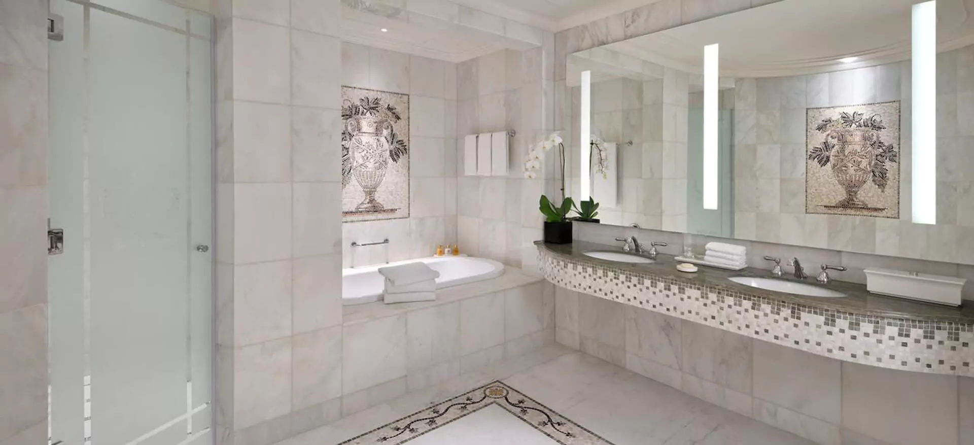 Mirror with integrated lighting inset in a tiled wall bathroom with sink.