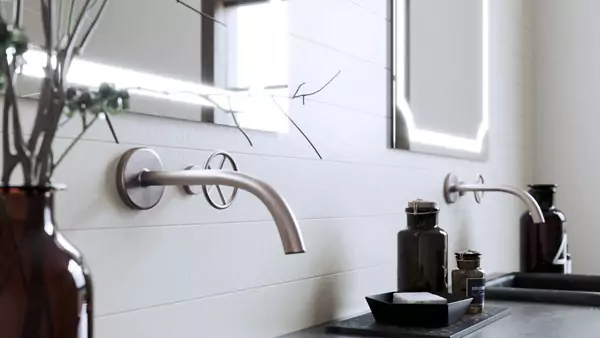 White wall with scalloped light mirror above a double faucet in a washroom.