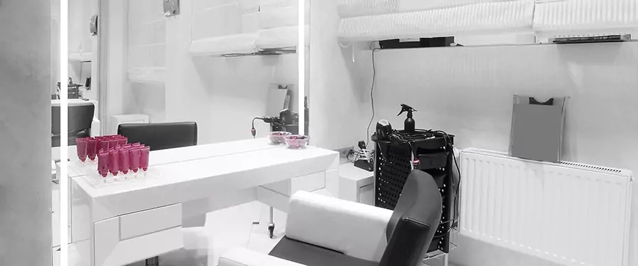 Salon trolley cart in a beauty studio with an illuminated full-length mirror and chair.