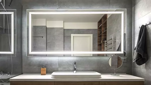 An icon of a custom-lighted mirror set into a wall above a single sink in a hotel bathroom.